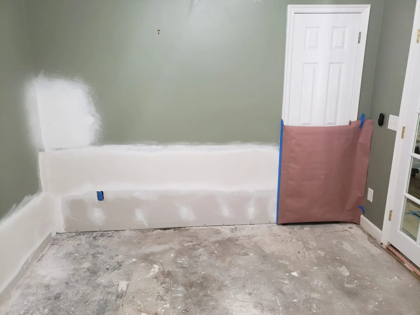 A room with the door open and paint on the floor.