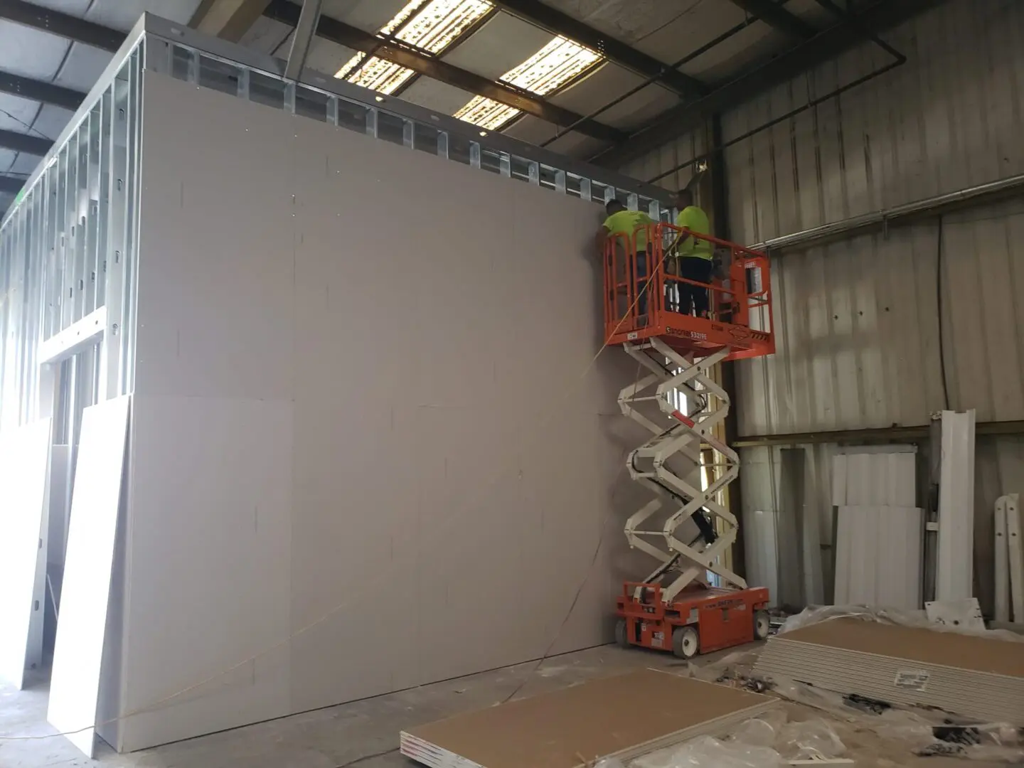A man on a scissor lift painting the wall.